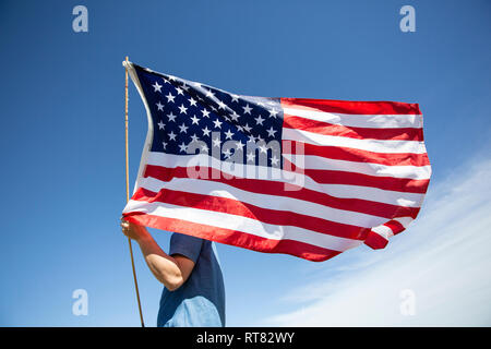 Man holding American flag under blue sky Banque D'Images