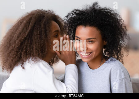 Fille africaine joyeux murmure à l'oreille des mères un secret Banque D'Images