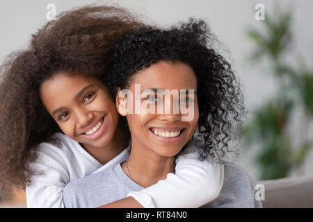 Heureux de l'Afrique mère et fille de câliner looking at camera Banque D'Images
