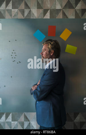 Businessman standing in front of magnet avec mur de post-it colorés mohican Banque D'Images