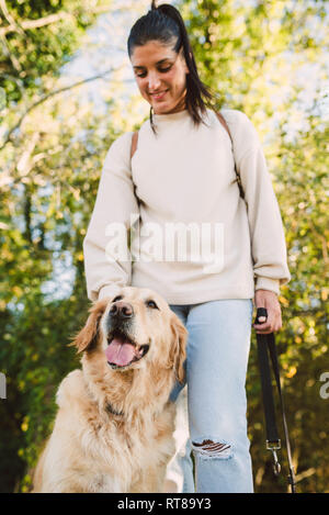 Jeune femme avec son chien golden retriever dans un parc Banque D'Images