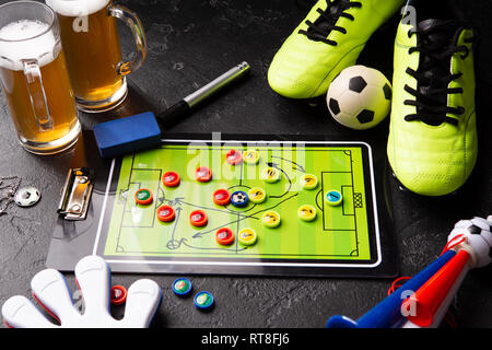 Photo de deux chopes de bière mousse, baby-foot, ballon, chaussures de football, tuyau, jouet hochet Banque D'Images