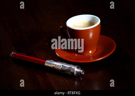 E-cigarette à côté d'une tasse de café. Expression de (moderne) plaisir et de détente. Banque D'Images