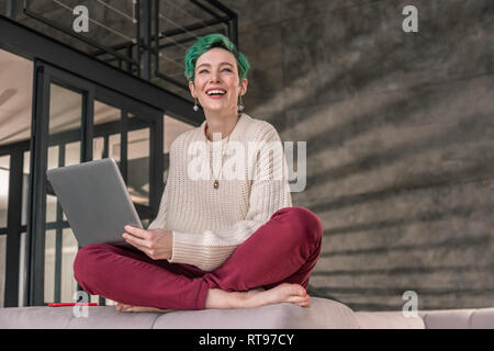 Femme aux yeux verts portant des accessoires intéressants travaillant à distance Banque D'Images