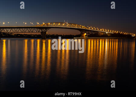 L'Auckland Harbour Bridge éclairés la nuit, une longue exposition à lisser l'eau, beaucoup de feux orange Banque D'Images