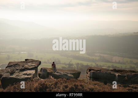 Grimpeurs sur Bamford Edge dans le Peak District, surplombant le paysage vers perdre Hill et Mam Tor dans la distance, un jour d'hiver Banque D'Images