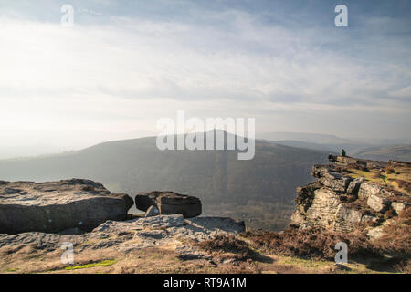 Grimpeurs sur Bamford Edge dans le Peak District, surplombant le paysage vers perdre Hill et Mam Tor dans la distance, un jour d'hiver Banque D'Images