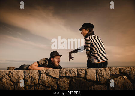 Les chefs d'élégant élégant couple leaning out des roches et merveilleux ciel avec des nuages Banque D'Images