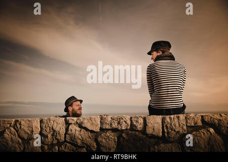 Les chefs d'élégant élégant couple leaning out des roches et merveilleux ciel avec des nuages Banque D'Images