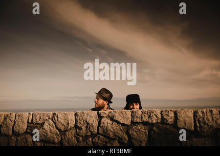 Les chefs d'élégant élégant couple leaning out des roches et merveilleux ciel avec des nuages Banque D'Images