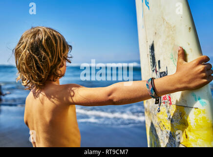 Le Chili, Puerto Maldonado, boy standing at the sea with surfboard Banque D'Images