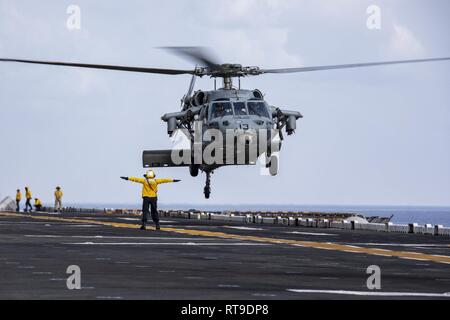 U.S. 5ÈME ZONE DES OPÉRATIONS DE LA FLOTTE (janv. 27, 2019) l'Aviation maître de Manœuvre (manutention) 2e classe Stephanie Vegaortiz dirige un MH-60S Sea Hawk qu'il décolle de l'envol du Wasp-classe d'assaut amphibie USS Kearsarge (DG 3). Kearsarge est le navire amiral de la groupe amphibie Kearsarge et, avec l'entrepris 22e Marine Expeditionary Unit, est déployé sur le 5e flotte américaine zone d'opérations à l'appui des opérations navales pour assurer la stabilité et la sécurité maritime dans la région Centrale, reliant la Méditerranée et le Pacifique à travers l'ouest de l'Océan Indien et t Banque D'Images
