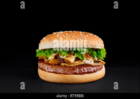 Hamburger parfait avec escalope de boeuf, champignons, laitue isolée au fond noir. Copy space Banque D'Images