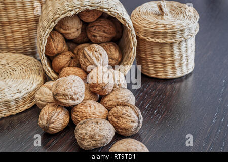 Ensemble de noix en panier et éparpillés sur une table en bois foncé, de l'espace pour le texte. Concept d'aliments sains. Banque D'Images