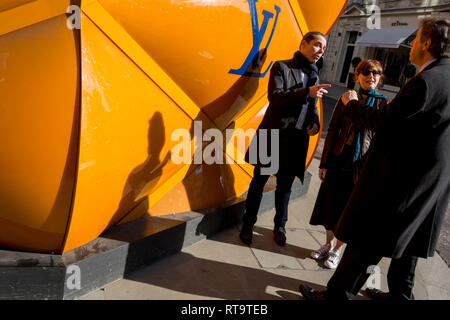 Associates de tenir une conversation après spontanément en heurtant les uns les autres sous l'amassage de rénovation temporaire de la marque de luxe Louis Vuitton à New Bond Street, le 27 février 2019, à Londres, en Angleterre. Banque D'Images