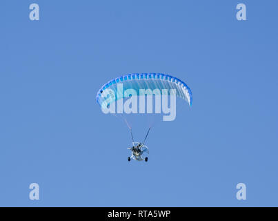 Parapente powered volant sous ciel bleu clair Banque D'Images