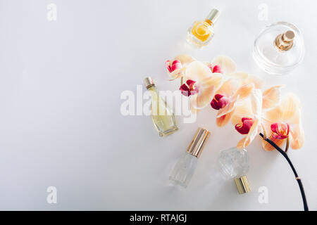 Flacons de parfum avec orchidée orange sur fond blanc. Parfum de fleur de produits cosmétiques bio. Space Banque D'Images