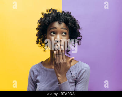 Secret, gossip concept. Jeune femme appelant à silence. femme isolé sur fond couleur mode studio. Jeune femme de l'Afrique de l'émotionnel. Les émotions humaines, l'expression faciale concept. Banque D'Images