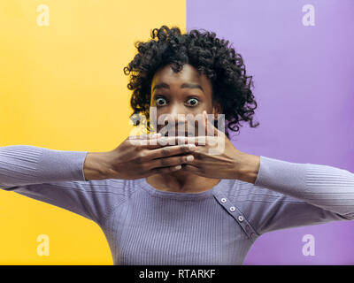 Secret, gossip concept. Jeune femme appelant à silence. femme isolé sur fond couleur mode studio. Jeune femme de l'Afrique de l'émotionnel. Les émotions humaines, l'expression faciale concept. Banque D'Images