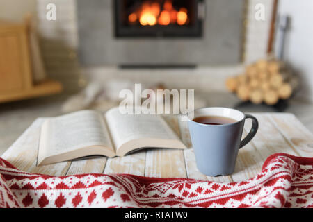 Réserver et tasse de thé près de cheminée. Hygge concept Banque D'Images