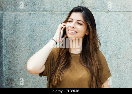 Rire d'Amérique latine young adult Woman talking on mobile phone extérieur en été Banque D'Images