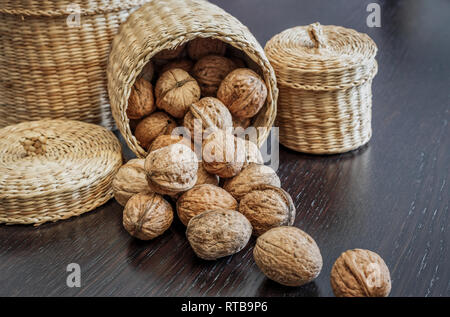 Ensemble de noix en panier et éparpillés sur une table en bois foncé, de l'espace pour le texte. Concept d'aliments sains. Banque D'Images