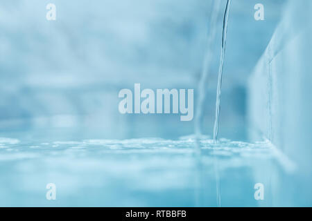 Un filet d'eau claire comme du cristal est versé dans la piscine. Focus sélectif très floues avec macro shot DOF peu profondes Banque D'Images