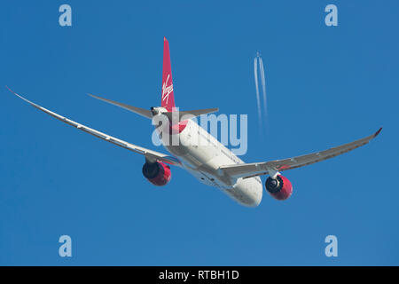 Virgin Atlantic un Boeing 787 Dreamliner de monter dans un ciel bleu, un Boeing 747 Contrailing à haute altitude au-dessus. Banque D'Images