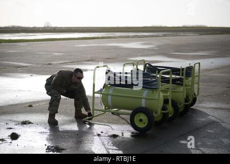 U.S. Air Force Tech Sgt. Christopher Brown, alerte transitoire sous-officier responsable affecté à la base aérienne 424e Escadron, déplace les extincteurs de la circulation comme les hélicoptères AH-64 Apache à partir de la 1re Brigade d'aviation de combat, 1re Division d'infanterie, quittent la base aérienne de Chièvres, Belgique, 7 février 2019. La Base Aérienne de Chièvres a servi comme une zone d'étape intermédiaire avant la 1re Brigade d'aviation de combat se déploie à l'Allemagne, la Pologne, la Lettonie et la Roumanie pendant neuf mois pour former avec les partenaires de l'OTAN à l'appui de la résolution de l'Atlantique. Banque D'Images