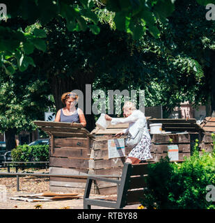 PARIS, FRANCE - 24 juin 2017 : les femmes adultes le compostage en milieu urbain dans les espaces dédiés dans la capitale française. Les gens le compostage mise en dépôt des déchets recyclage composteur. Banque D'Images