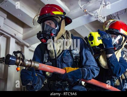 Mer Méditerranée (fév. 11, 2019) pompier Liam McCann de Glen Ridge, N.J., gauche, et dommages 3e classe Controlman Austin Aubrey de Bradenburg, Ky. lutter contre un incendie simulé au cours d'un exercice général quarts à bord du San Antonio-classe de transport amphibie USS station d'Arlington (LPD 24), le 11 février 2019. Arlington est sur un déploiement prévu dans le cadre du groupe amphibie Kearsarge en soutien d'opérations de sécurité maritime, d'intervention en cas de crise et le théâtre de la coopération en matière de sécurité, en offrant également une présence navale de l'avant. Banque D'Images