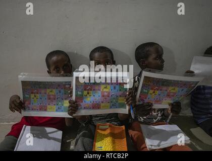 Les enfants d'utiliser la lecture sida au cours d'une discussion en anglais groupe mené par des soldats de l'Armée américaine à partir de la Compagnie Bravo, 404e Bataillon des affaires civiles, affecté à la Force opérationnelle combinée Force-Horn de l'Afrique, à Tadjoura, Djibouti, le 12 février 2019. Plus de 90 jeunes et adultes djiboutienne est allé(e) à un groupe où les élèves à développer des compétences pratiques et linguistiques par le biais de conversations avec rhétorique anglophones membres service aux États-Unis. Banque D'Images