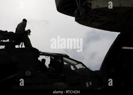 Les aviateurs, soldats, et le personnel se préparer pour charger les hélicoptères Apache en un C-5 à l'aérodrome de Bagram, en Afghanistan, le 20 février, 2019. Les troupes doivent travailler ensemble pour assurer l'Apache 'clear' le C-5 lors du processus de chargement. Banque D'Images