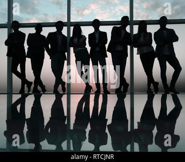 Silhouette d'une équipe entreprises debout à côté de la fenêtre du bureau Banque D'Images