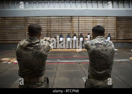 Lance le Cpl. Andrew Foss et le Cpl. Andre Balseca, riflemen avec la Compagnie Alpha, l'Équipe de débarquement du bataillon, 1er Bataillon, 4ème marines, la Chine "marines", simuler le feu M9A1 9 mm pistolets de service à bord du navire de débarquement dock USS Ashland (LSD 48), mer de Chine orientale, le 14 février 2019. Foss, natif de Milwaukee, Wisconsin, est diplômé de l'Université Riverside en juin 2017 avant de s'enrôler plus tard ce mois. Balseca, originaire de Chicago, Illinois, est diplômé de l'East High School de Leyden Mai 2015 avant de s'enrôler en juin plus tard cette année. La Compagnie Alpha marines sont le petit bateau raid specialists pour BLT 1/4, Banque D'Images