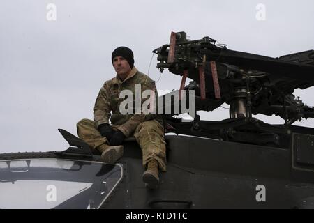 Les aviateurs, soldats, et le personnel se préparer pour charger les hélicoptères Apache en un C-5 à l'aérodrome de Bagram, en Afghanistan, le 20 février, 2019. Les troupes doivent travailler ensemble pour assurer l'Apache 'clear' le C-5 lors du processus de chargement. Banque D'Images