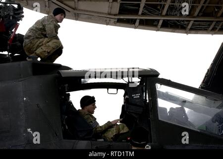 Les aviateurs, soldats, et le personnel se préparer pour charger les hélicoptères Apache en un C-5 à l'aérodrome de Bagram, en Afghanistan, le 20 février, 2019. Les troupes doivent travailler ensemble pour assurer l'Apache 'clear' le C-5 lors du processus de chargement. Banque D'Images