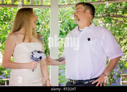 Les nouveaux mariés rire comme ils parlent après leur cérémonie de mariage au parc Marshall à Ocean Springs, Mississippi. Banque D'Images