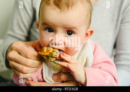 4 mois du grignotage une cuisse de poulet, sa première dégustation des aliments à l'aide de la méthode de sevrage led Bébé BLW. Banque D'Images