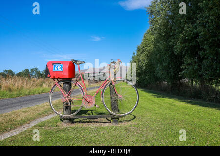 Une boîte aux lettres boîte aux lettres rouge attaché à une course vélo de route sur une route de campagne en milieu rural de l'île du sud de Nouvelle-Zélande Banque D'Images