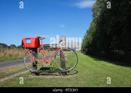 Une boîte aux lettres boîte aux lettres rouge attaché à une course vélo de route sur une route de campagne en milieu rural de l'île du sud de Nouvelle-Zélande Banque D'Images