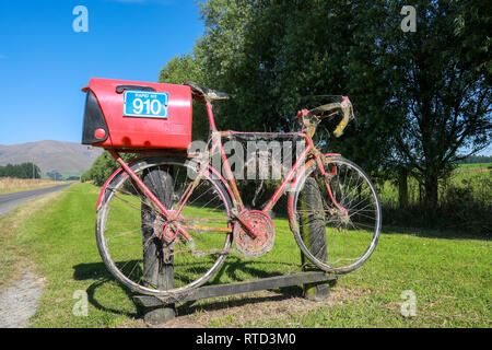 Une boîte aux lettres boîte aux lettres rouge attaché à une course vélo de route sur une route de campagne en milieu rural de l'île du sud de Nouvelle-Zélande Banque D'Images