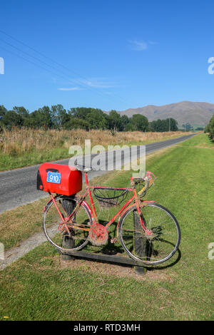 Une boîte aux lettres boîte aux lettres rouge attaché à une course vélo de route sur une route de campagne en milieu rural de l'île du sud de Nouvelle-Zélande Banque D'Images