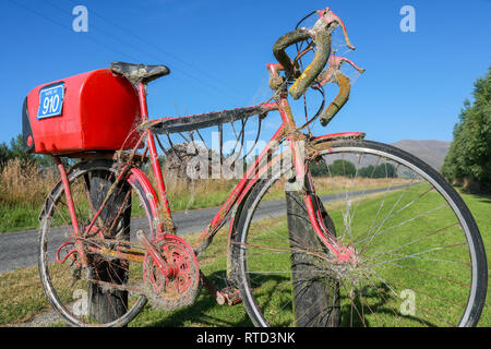 Une boîte aux lettres boîte aux lettres rouge attaché à une course vélo de route sur une route de campagne en milieu rural de l'île du sud de Nouvelle-Zélande Banque D'Images