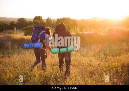 Les voyageurs avec sac à dos marche dans le coucher du soleil à l'extérieur. Banque D'Images