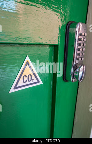 Triangle de CO2 Panneau d'avertissement et clavier numérique serrure de porte sur une ancienne porte en bois vert à Doncaster, Angleterre Banque D'Images