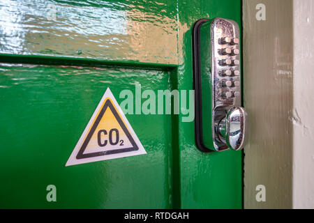 Triangle de CO2 Panneau d'avertissement et clavier numérique serrure de porte sur une ancienne porte en bois vert à Doncaster, Angleterre Banque D'Images