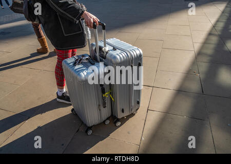 Jeune femme tire ses deux Manoukian Assurance définir les cas d'aluminium hors de la gare de Kings Cross, Londres, Angleterre Banque D'Images