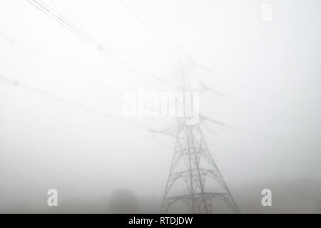 Low angle view électricité pylône dans le brouillard au petit matin Banque D'Images
