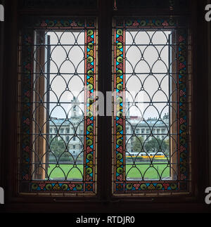 Vieille fenêtre au plomb dans l'édifice du Parlement de la Hongrie a motif floral coloré. Un autre bâtiment élégant et tramway jaune sont visibles dans la distance Banque D'Images